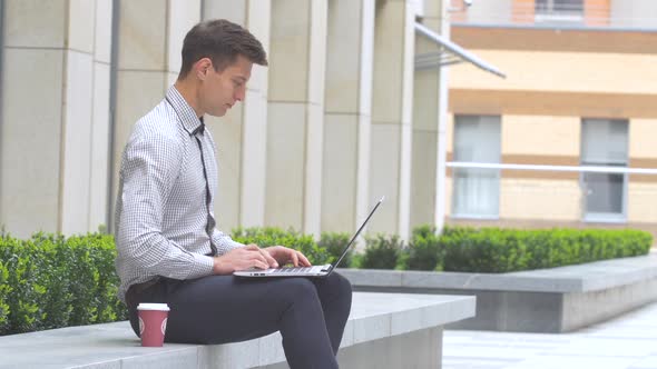 Businessman Sitting Outdoors with Laptop