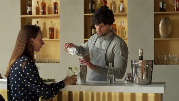 Man Bartender Working Preparing Cocktails at the Bar Talking to His Woman Client