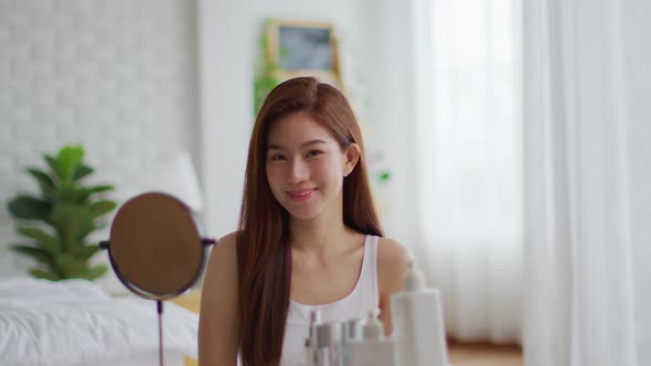Happy Asian young woman smile and looking in camera doing skin care