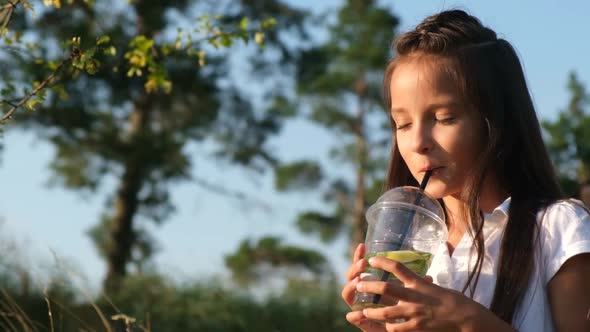 Little Girl Drinks a Cold Cocktail on a Hot Summer Day