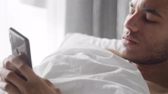 Face of Man Using Smartphone in Bed