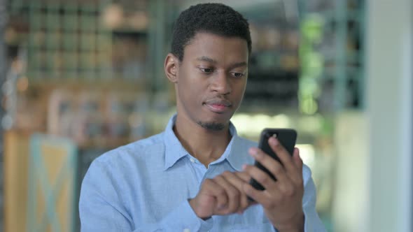 Positive Young African Man Using Smartphone 
