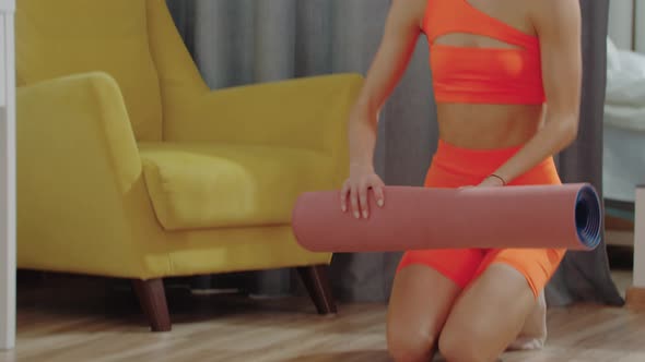 A Young Woman Lays Down a Yoga Mat in the Room