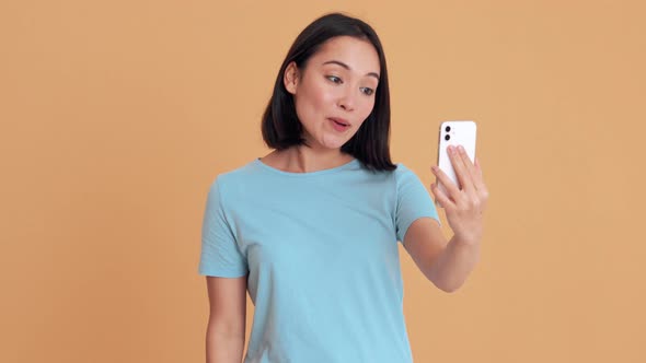 Cheerful woman in blue t-shirt talking by video call on phone