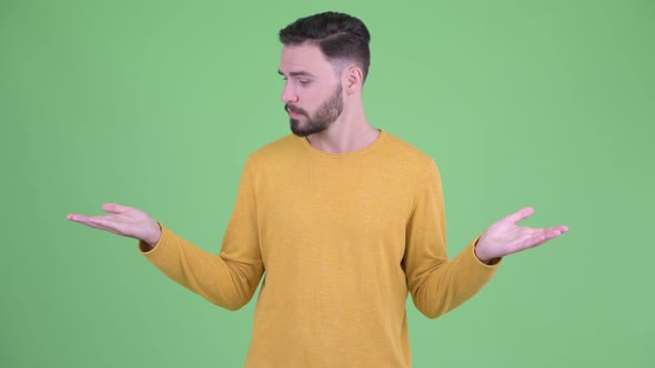 Happy Young Handsome Bearded Man Comparing Something