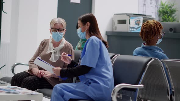 Asian Nurse Consulting Senior Woman with Face Mask in Hospital Reception Lobby