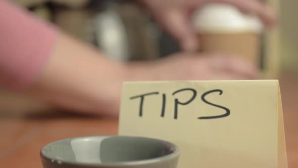 Tipping bowl in cafe with person getting coffee in background