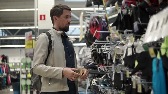 Male Customer is Trying on a Sport Glasses in a Trading Hall of Big Store