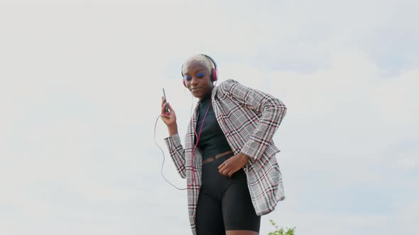 Young woman with headphones and smartphone dancing to music