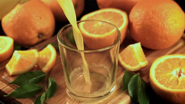 A Stream of Orange Juice Pours Into the Glass in a Whirlpool