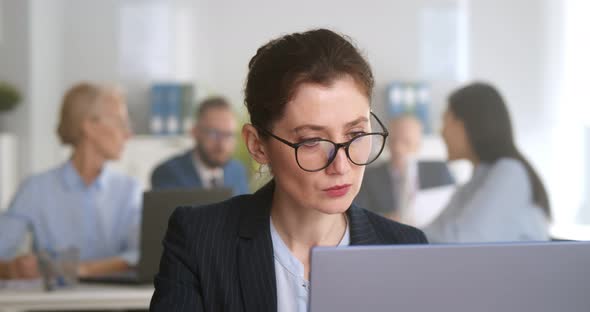 Charming Caucasian Businesswoman Sitting Working on Laptop in Office