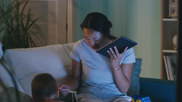 Asian Mother Eating and Speaking on Tablet