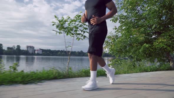 Muscular African Man Running Along the City Lake