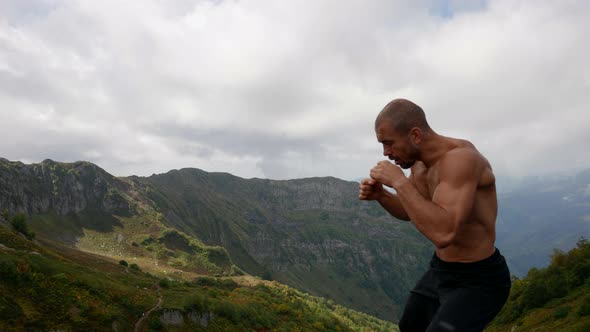 Muscular Fighter is Training Alone at Top of Mount Naked Torso Waving Hands