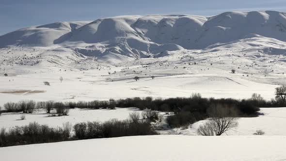 Tree Stream in Snow Covered Meadow in Sunny Winter Day