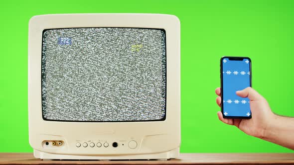 Old Television with Grey Interference Screen on Green Background and Smartphone with Blue Chroma Key