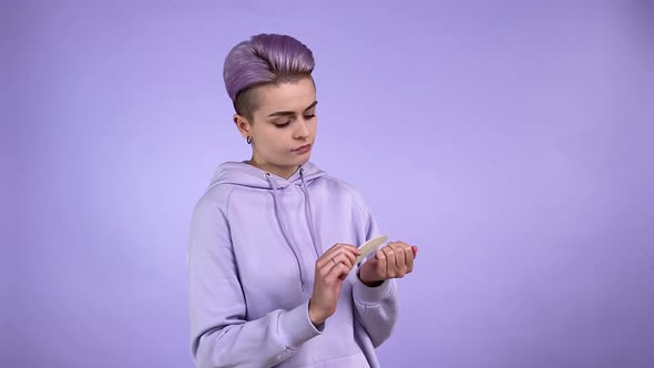 Trendy Lesbian in Hoodie Manicuring with Nail File Indoors