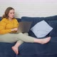Woman is Sitting on the Sofa with Laptop and Typing Something - VideoHive Item for Sale