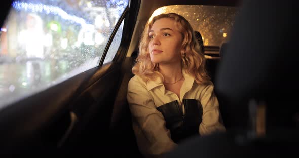 Beautiful Woman Sitting in the Car and Looking Out the Window