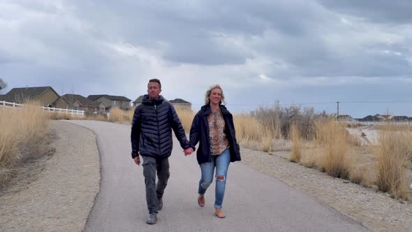 Couple walking along a neighborhood trail towards the camera - pedestal downement with the couple wa