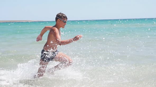 Teen Child Runs Across the Azure Sea and Falls Jumps Into the Water on a Sunny Day Slowmotion Video