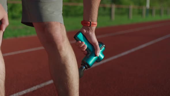 An Athlete Massages with a Percussion Therapy Gun to Relieve the Pain of Muscle Aches After a