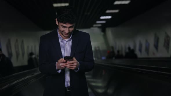 Smiling Businessman with Smartphone on Escalator