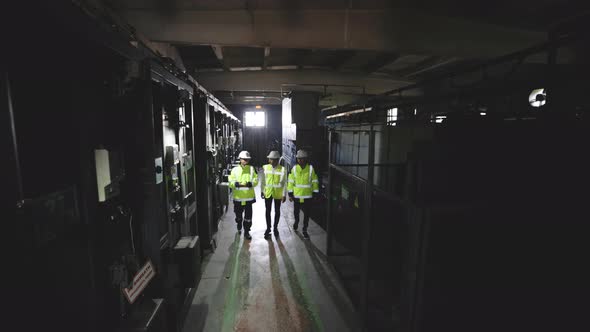 Three Multiethnic Team of Industrial Engineers Walking in Manufacturing Plant Discussing New Project