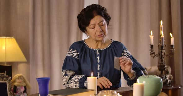 Concentrated Caucasian Senior Woman Taking Out Cards From Card Deck and Putting Them on the Table