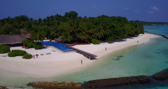 Daytime overhead tourism shot of a sandy white paradise beach and aqua blue water background in hi r