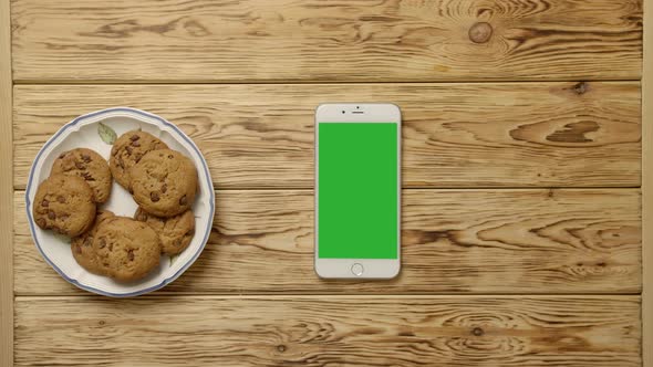 Crop Person Drinking Coffee and Eating Cookies Near Smartphone