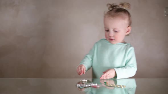 A little girl finds pills on the table and plays with them