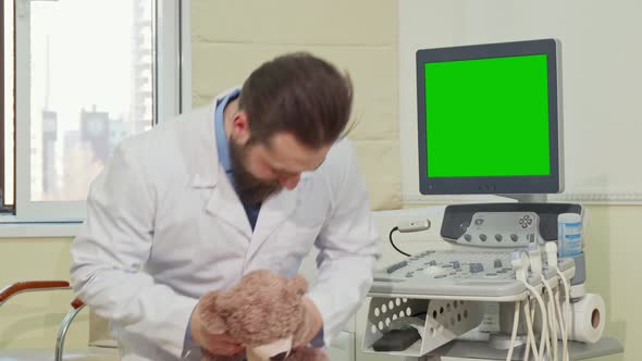 Pediatrician Holding Teddy Bear, Ultrasound Scanner with Green Screen on the Back