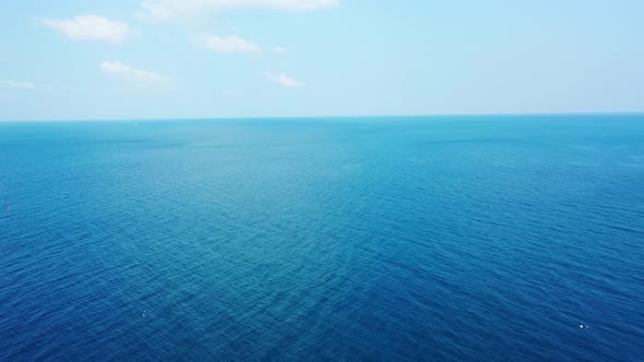 Abstract deep sea background. Aerial backwards revealing bright blue sky with white clouds