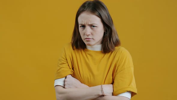 Portrait of Offended Girl Looking at Camera with Discontent and Blame Standing Against Yellow