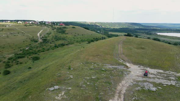 Man in a Black Cap and Red T-shirt on a Colored ATV Rides