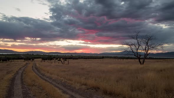 Time lapse of dirt road leading into colorful sunset in dry grass land