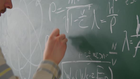 Close Up Teacher Man Hand Writing Math Formulas on Chalkboard with White Chalk