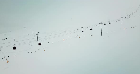 Aerial shot of skiing gondola lifts in heavy snowing and foggy weather