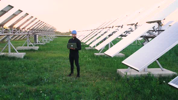 Engineer Working Using Laptop Stand Next To Solar Batteries