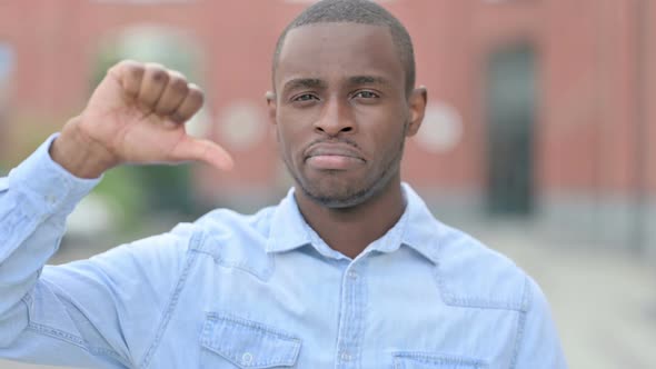Outdoor Portrait of Disappointed African Man Doing Thumbs Down