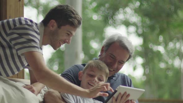 Boy with father and grandfather using digital tablet