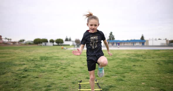 A young athlete has fun practicing her running form at the park.