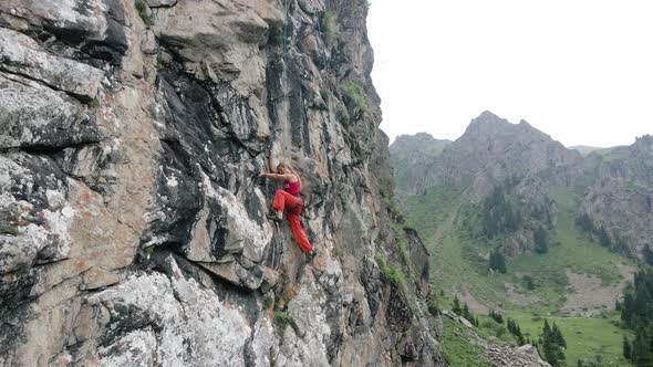 Woman Athlette Climbing on the High Rock in the Mountains