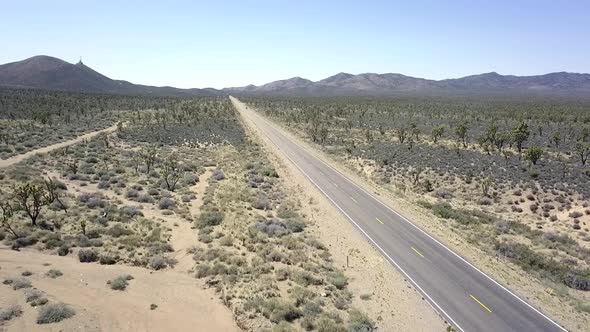 An empty grade black road in no man's land. Spectacular aerial view flight fly backwards drone foota