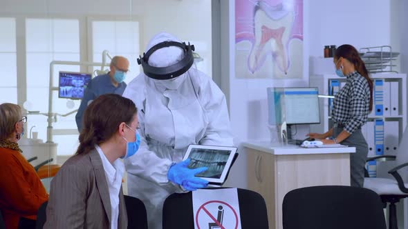 Stomatologist in Protective Suit Pointing on Digital Xray