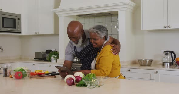 African american senior couple having a video call on digital tablet in the kitchen at home
