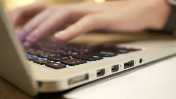 Blurred close up hands typing on laptop keyboard