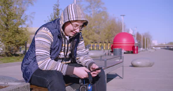 Smartphone Addiction Concept Teenage Boy with Smartphone and Headphones in His Hands He Chatting