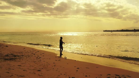 Man alone angling on idyllic shore beach time by clear water and clean sandy background of Lombok is